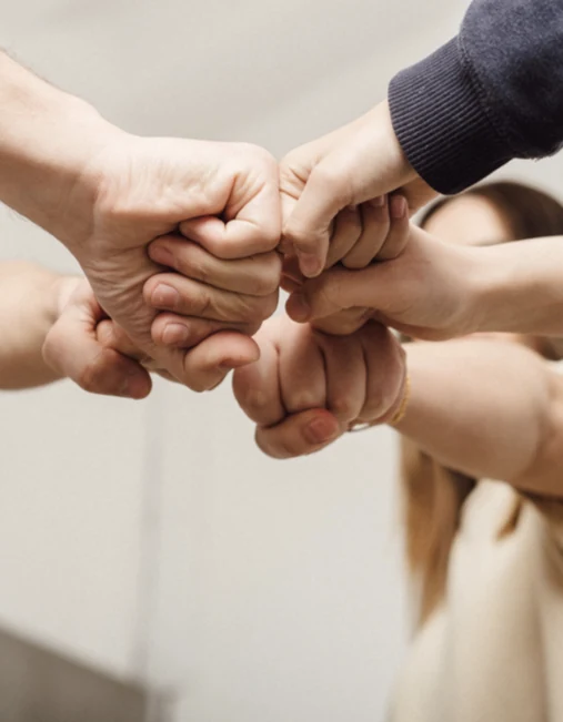 Hands of several people joined together in the center of a circle